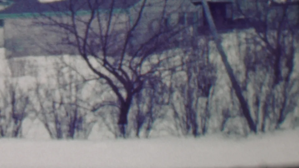 Grand Rapids, Michigan home-movie frame from 1958 showing a snow-covered residential yard and driveway with a light-colored car partly entering from the right.