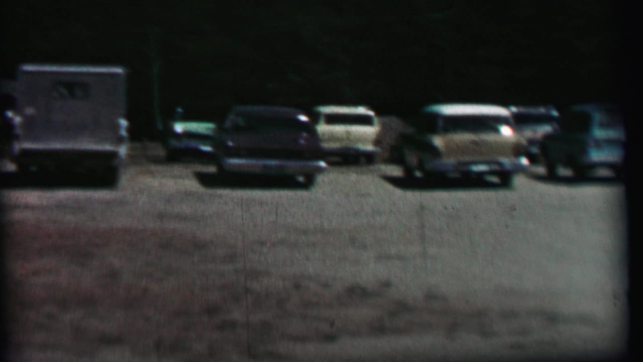 Parked cars and utility vehicles lined up across a gravel lot.