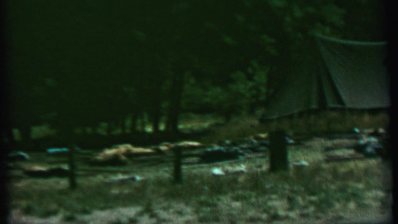 1967 Farragut State Park frame showing a small canvas tent in a shaded wooded campsite with a split-rail fence and scattered camping items.