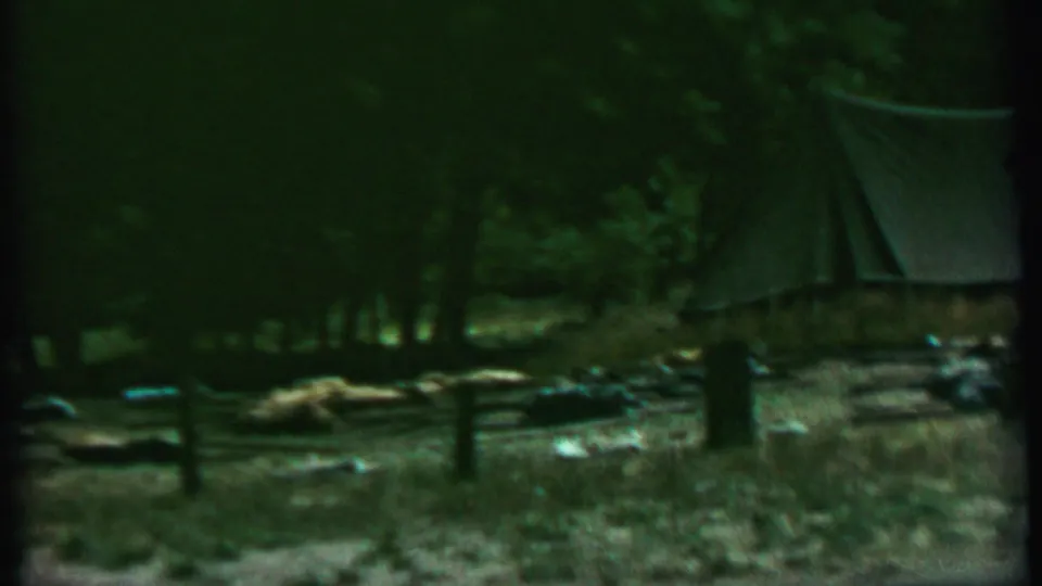 1967 Farragut State Park frame showing a small canvas tent in a shaded wooded campsite with a split-rail fence and scattered camping items.