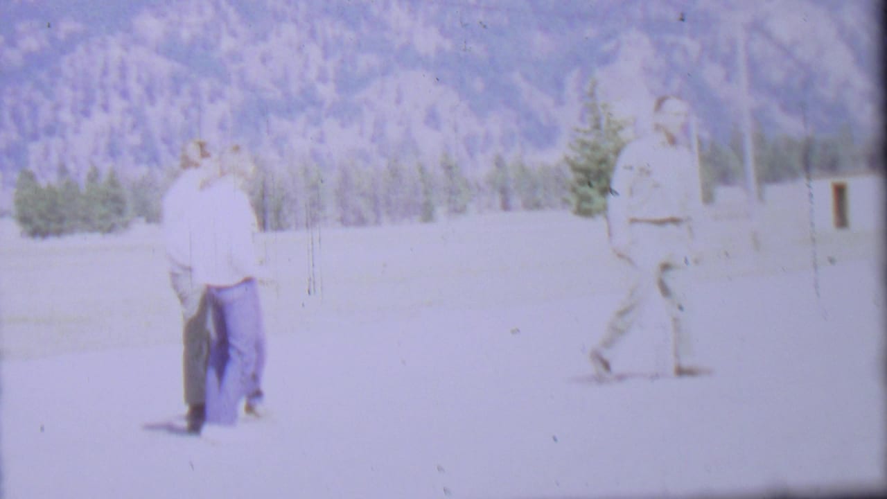 Two men stand near the center while a third man walks at right beside a small upright object.