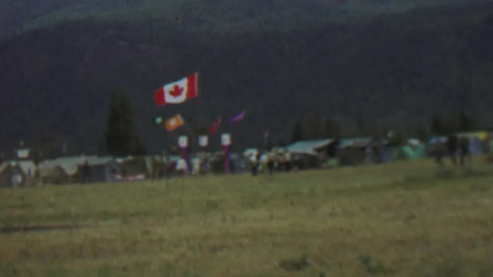 Farragut State Park camp view from 1967 with the Canadian flag, several tents, small banners, and distant figures spread across a grassy field.