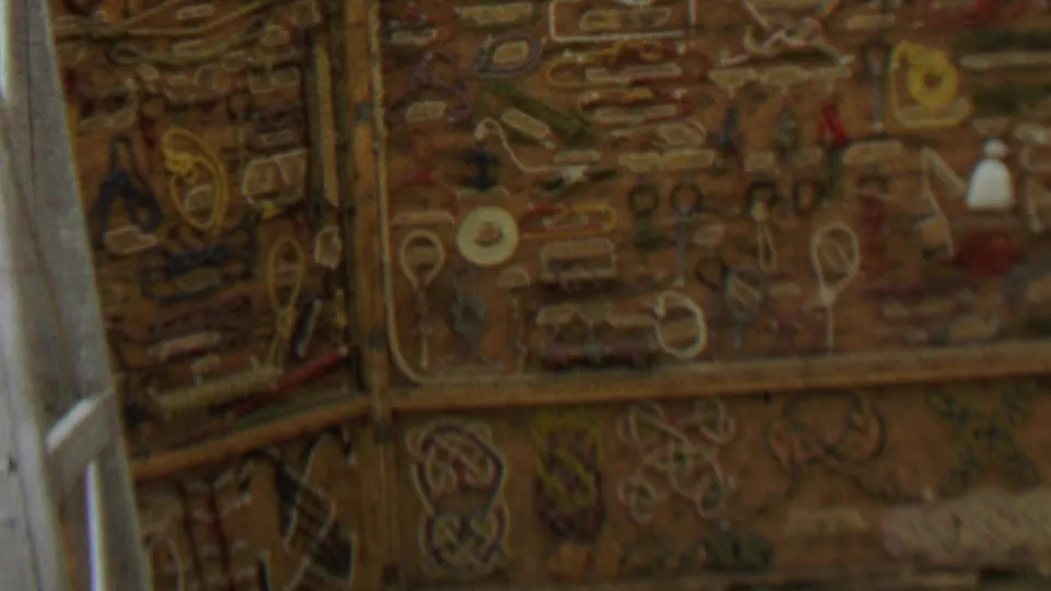 1967 8mm frame from Farragut State Park, Idaho, showing a close, soft-focus view of ornate embroidered or stitched wall decoration beside a pale vertical frame.