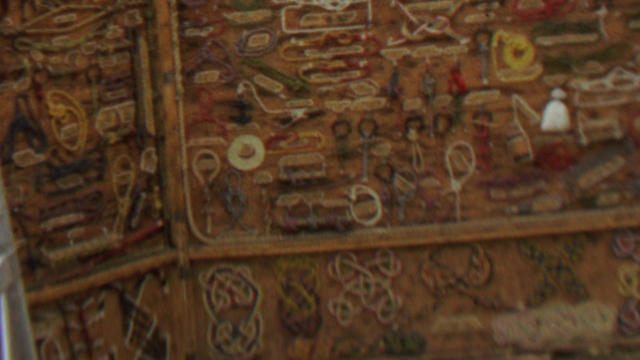 Decorative brown wall covering with stitched loops, small shapes, and a pale vertical edge at left.