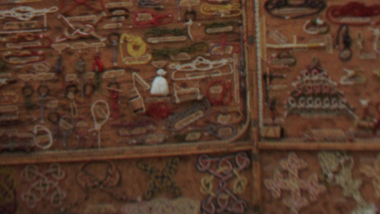 Handmade textile display with colorful stitched motifs and small arranged craft objects.