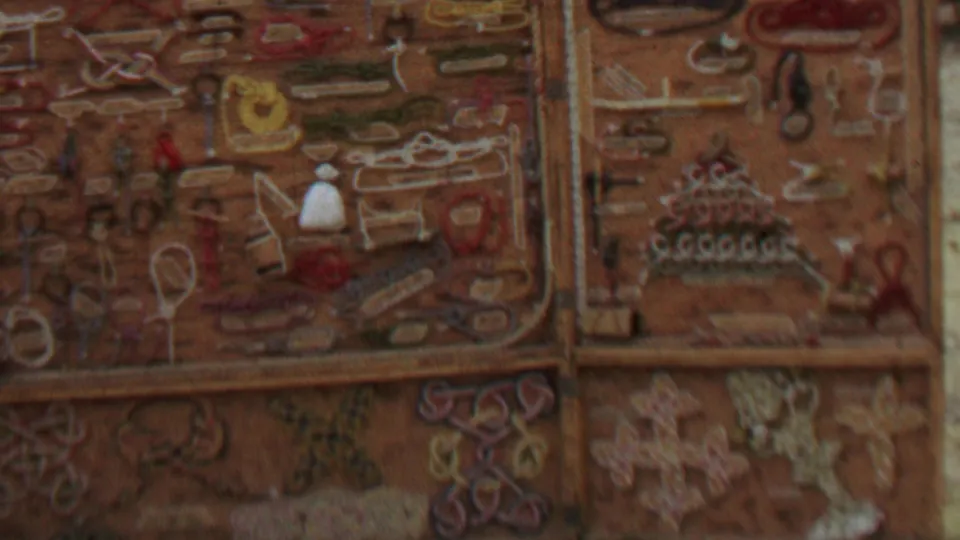 1967 8mm close-up of handmade knickknacks and embroidered or appliqued designs arranged across a divided display surface in the United States.