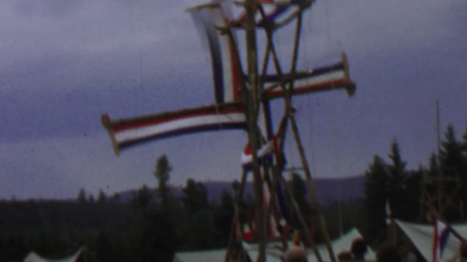 1967 8mm frame from Farragut State Park, Idaho, showing a wooden Dutch-style windmill display with red, white, and blue striped sails over festival tents and evergreens.
