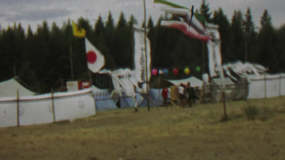 1967 Farragut State Park festival view with a Japanese flag and yellow flag beside vertical banners, white tenting, carp streamers, colored balloons, and visitors gathered near the entrance.
