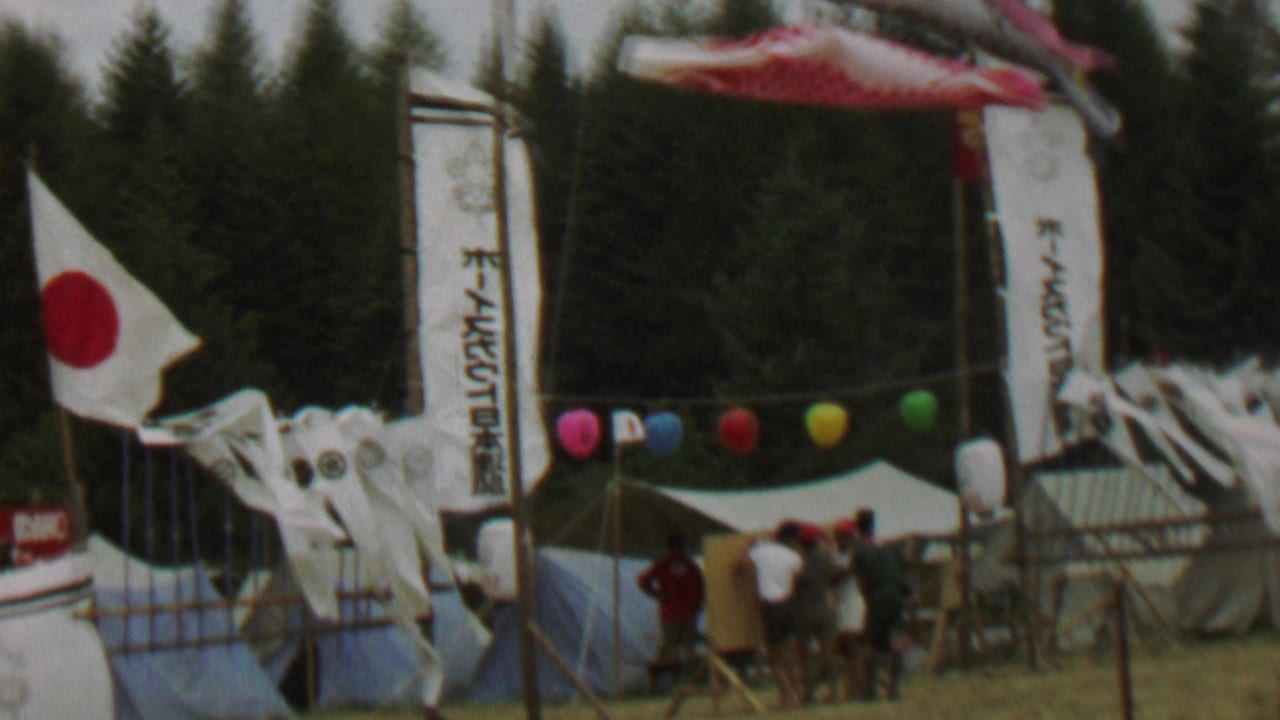 Windblown Japanese flag, carp streamers, banners, balloons, tents, and gathered attendees.