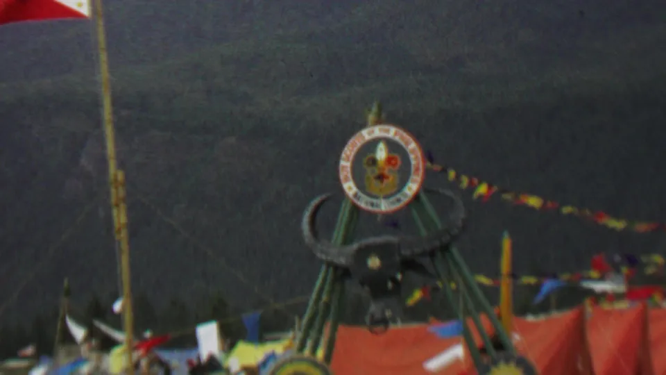 Wider 1967 Farragut State Park frame showing the bull's head attraction on green supports, the Boy Scouts of the Philippines emblem above it, strings of pennant flags, orange fabric, and surrounding outdoor event structures.