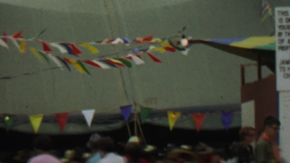 Colorful pennants span the outdoor trading post area at Farragut State Park, with tents, attendees, and the edge of the sign visible in the 1967 home-movie frame.
