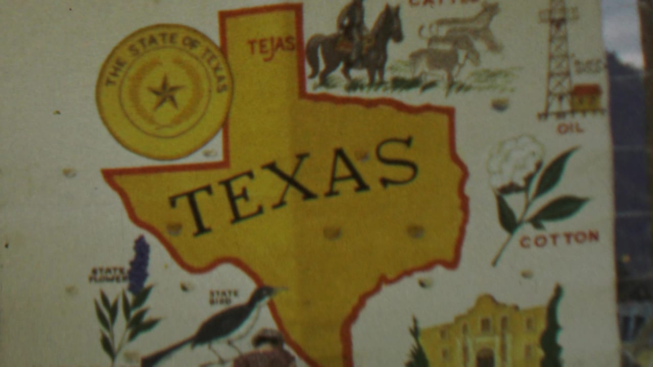 1967 8mm home-movie frame showing a colorful Texas souvenir poster with a yellow map, state seal, cowboy, cattle, oil derrick, cotton, bluebonnet, and Alamo illustrations.