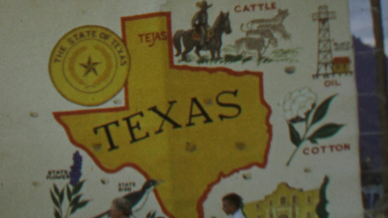 1967 8mm frame showing a Texas state display sign with seal, map outline, cattle, oil rig, cotton illustration, and partial visitors at the lower edge.