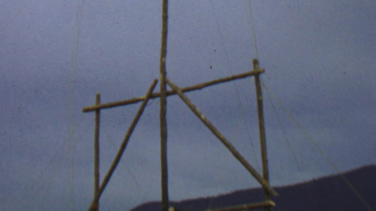 Wooden flagstaff structure against cloudy sky and distant hills.
