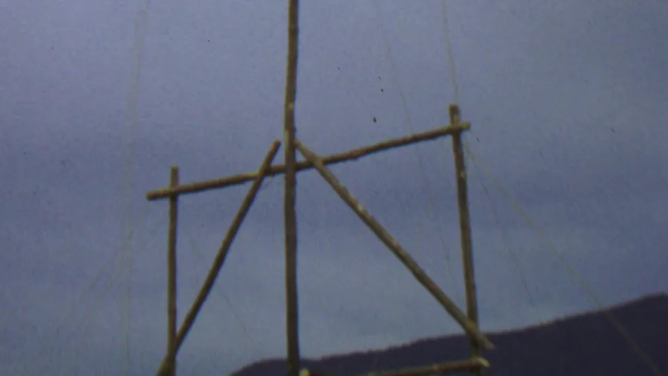 Wooden poles form a simple flagstaff or frame against a cloudy sky, with dark hills visible along the lower edge in the supplied Farragut State Park context.