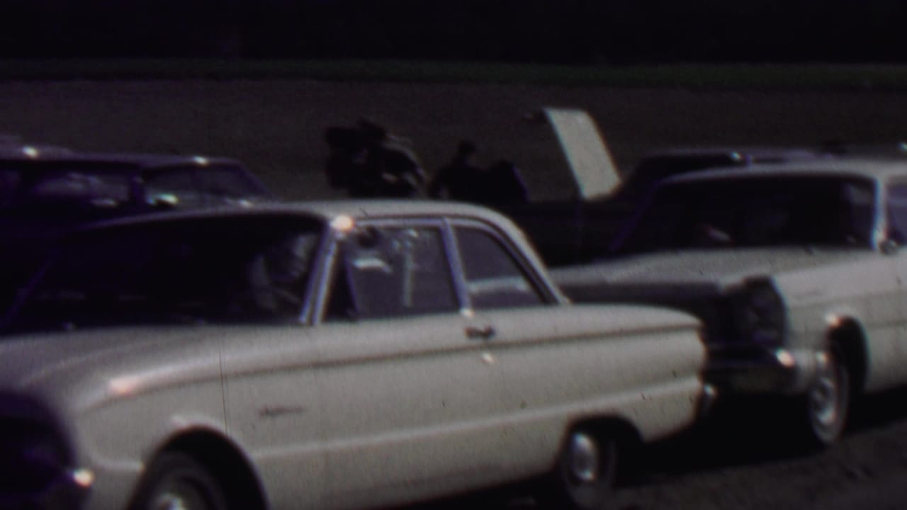 White sedan in foreground with darker cars and a station wagon behind it.