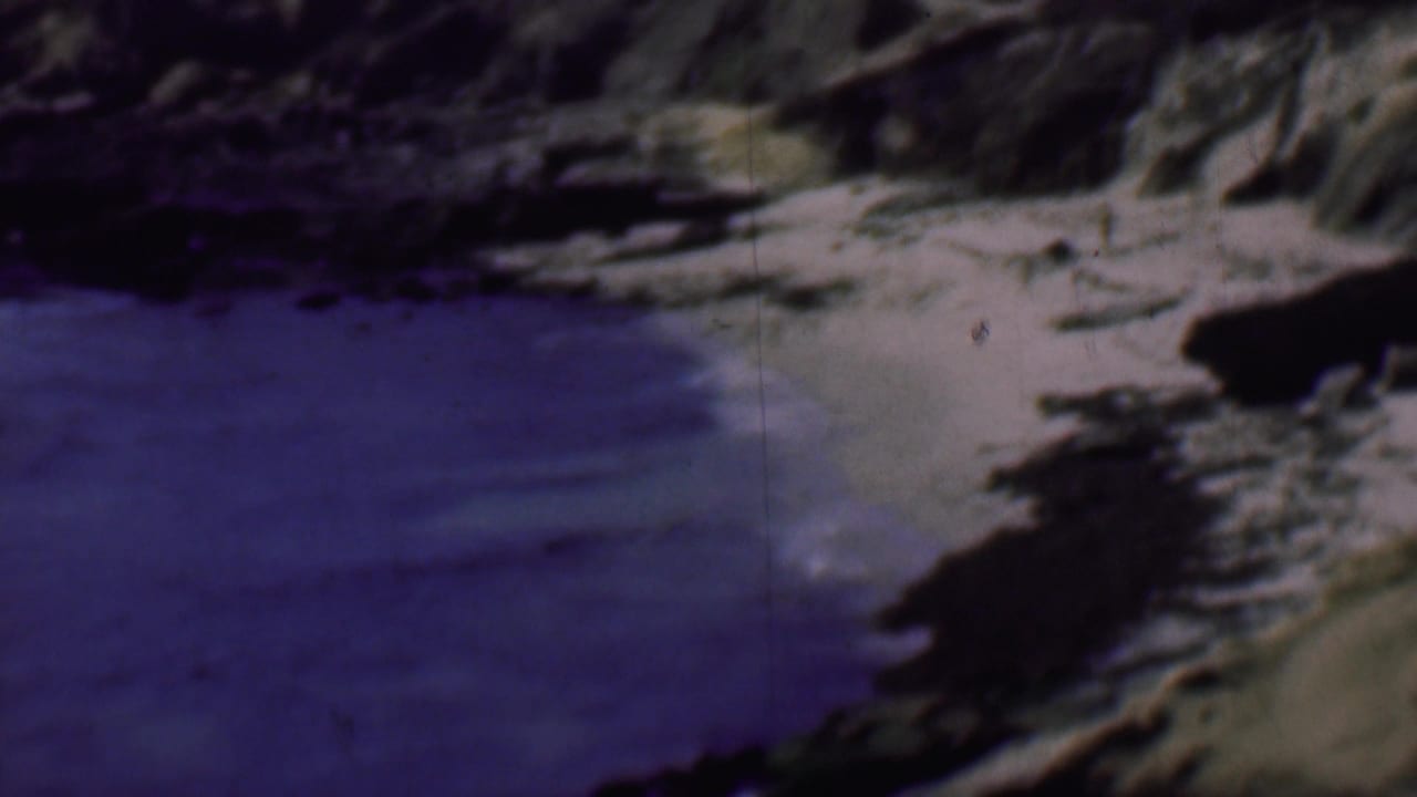 Small beach curve with blue water and rocks along the shoreline.