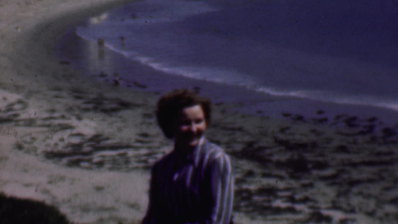 Woman smiling near the right side of the frame with beach and surf behind her.