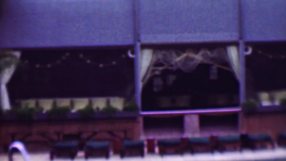 1961 San Diego exterior view of a restaurant or hospitality building with decorative curtains, string lights across the facade, planter boxes, and poolside lounge chairs.