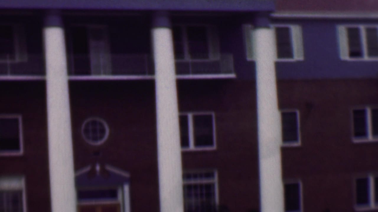 Upper facade with white columns, dark balcony openings, and rows of windows.