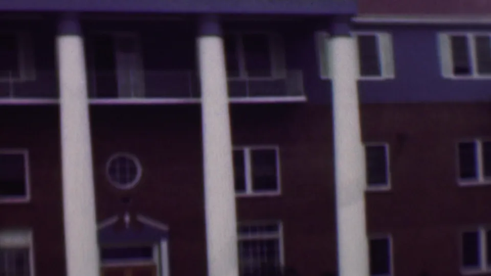 1961 San Diego exterior view of a formal red brick building with prominent white columns, shaded balcony openings, and multiple rectangular windows.