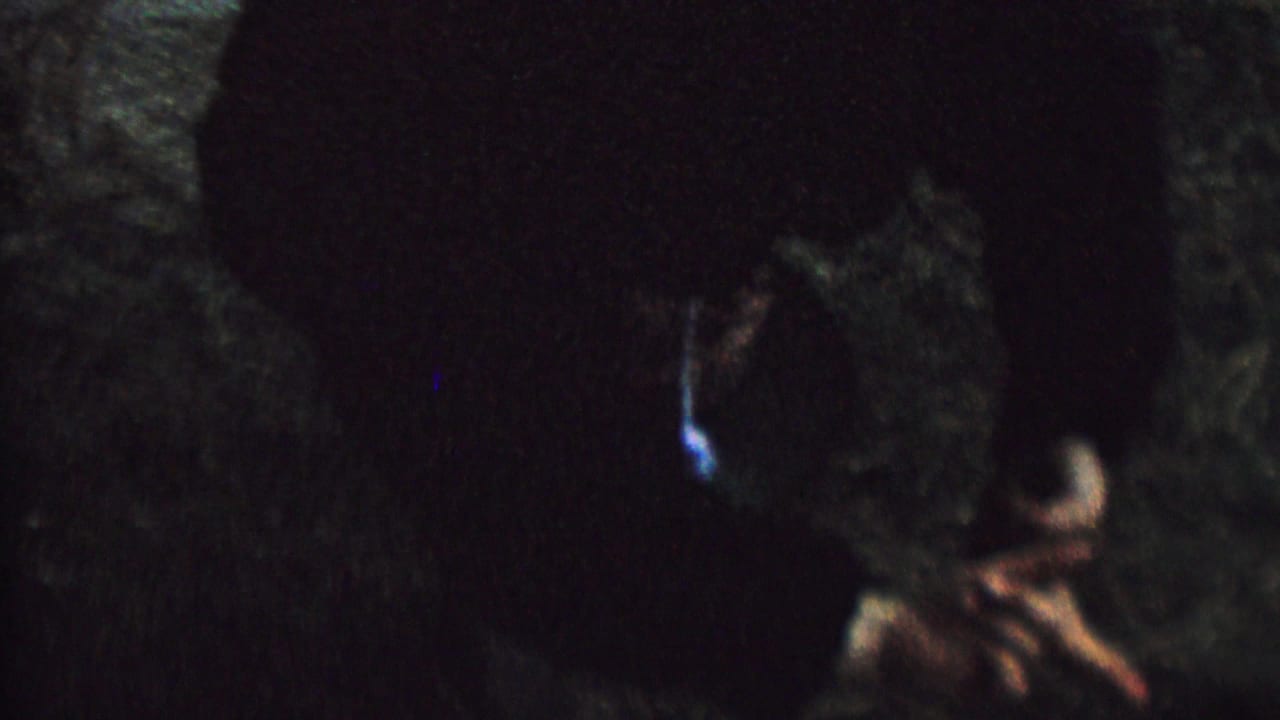 Blurred upside-down child in a dark outdoor frame with face partially lit.