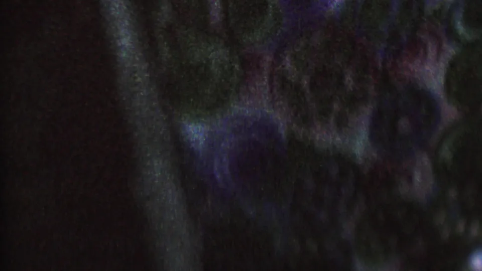 A dark, grainy closing frame shows indistinct shapes and blue-purple color shifts, with a possible partial figure or clothing edge but no clear location detail.