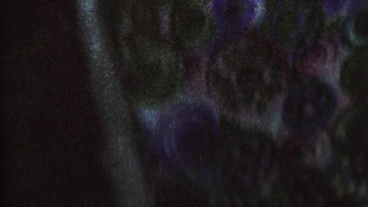 Low-light 1962 8mm frame from the supplied St. Paul home-movie clip showing indistinct adults in a staged dramatic scene with heavy grain and color distortion.