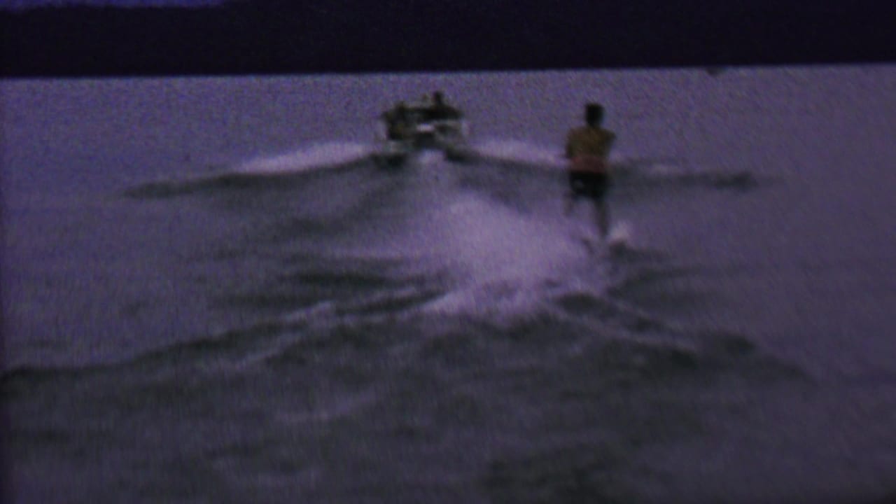 Speedboat pulls a water skier across choppy water.