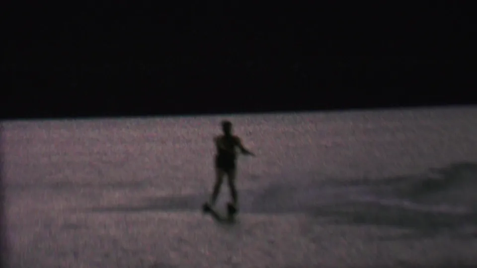 The skier remains upright on water skis near the lower left of the frame, seen as a dark figure against the dim lake surface.