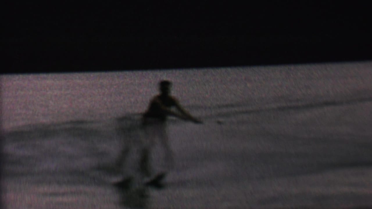 In 1962 home-movie footage from the St. Paul, Minnesota area, a distant man appears silhouetted while water skiing across a dim lake surface.