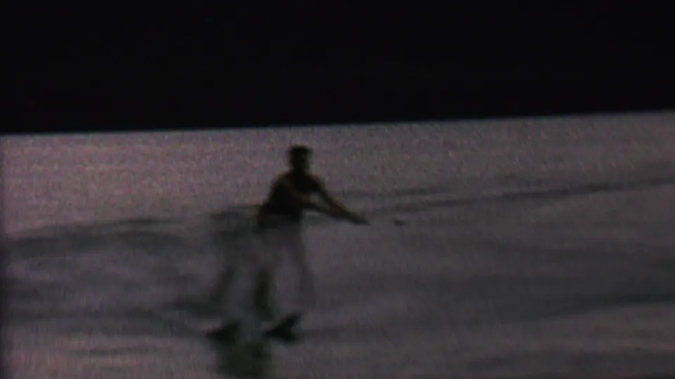 In 1962 home-movie footage from the St. Paul, Minnesota area, a distant man appears silhouetted while water skiing across a dim lake surface.