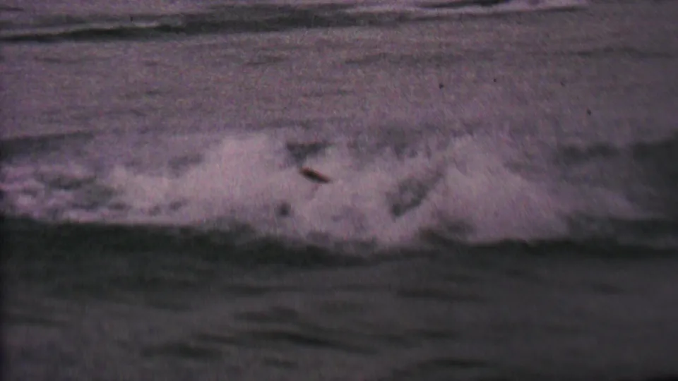 A splash and disturbed wake show the skier down in the water, with only a small dark shape visible against the rippled lake surface.