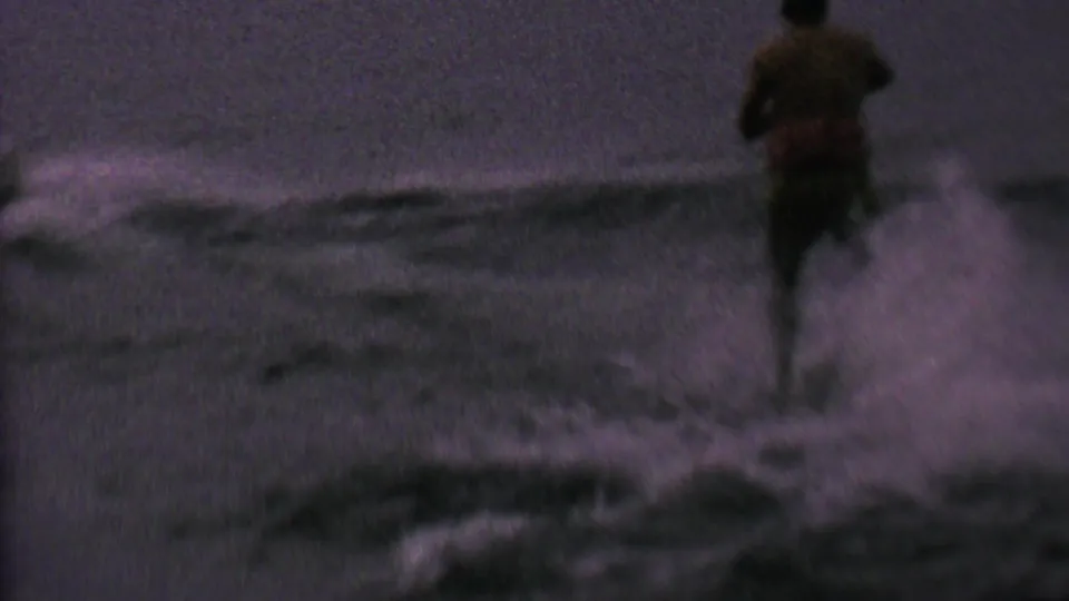 A distant waterskier appears on a lake in archival 8mm footage from the supplied 1962 St. Paul, Minnesota metadata, with wake and spray surrounding the skier.