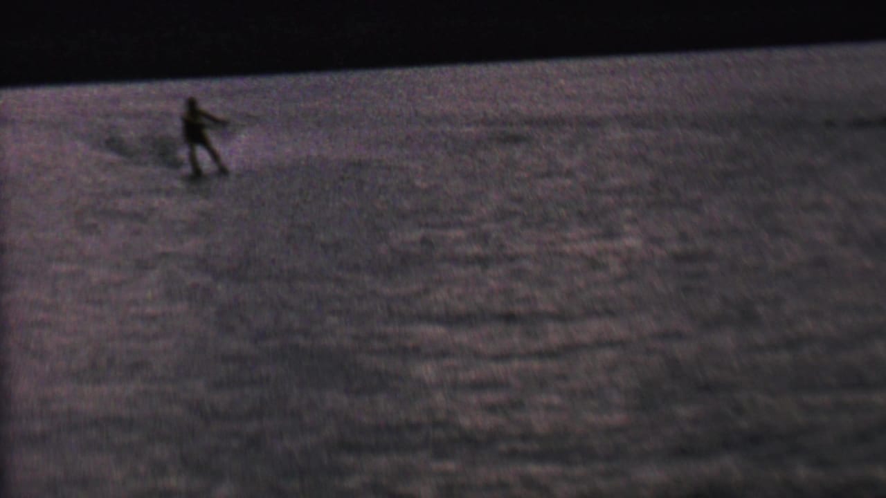 Small water skier silhouette moving across rippled water.