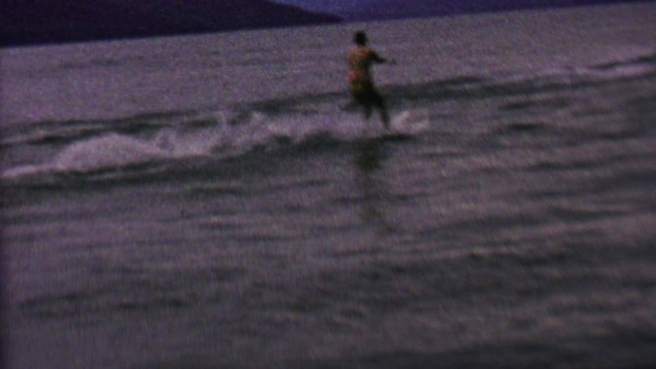 Water skier moves across the lake as wake spreads behind the tow line.