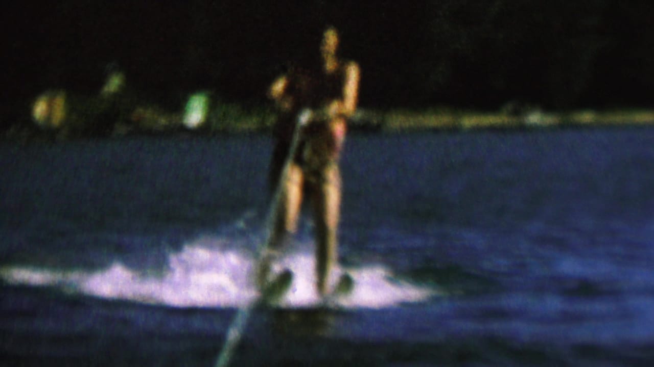 Water skier standing on the wake while holding a tow rope at night.