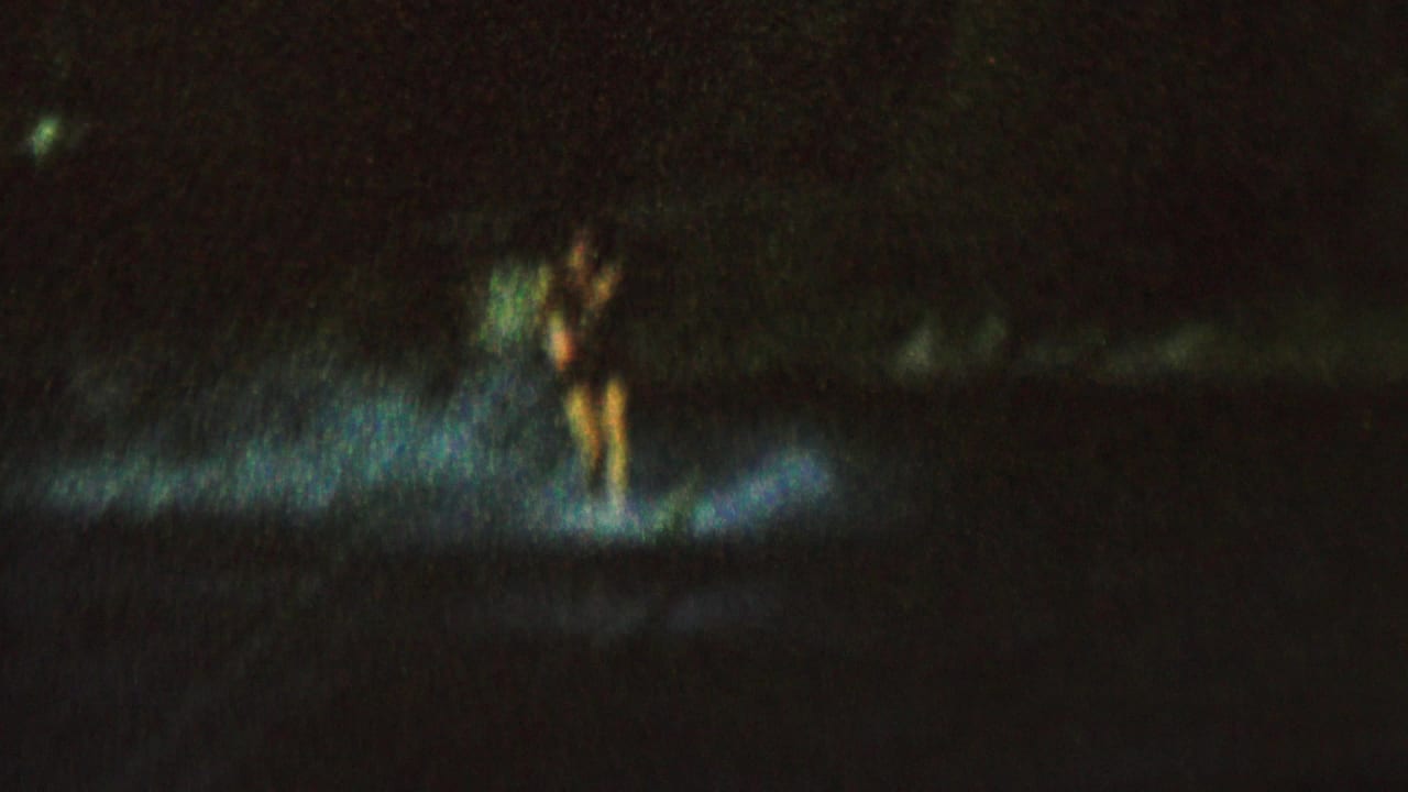 A water skier is lit by a bright patch of light on dark water.