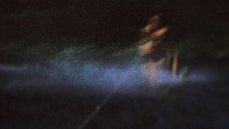 The female water skier is closest and most visible here, leaning at the edge of a blue-white spotlight trail on dark lake water in the supplied 1962 St. Paul context.