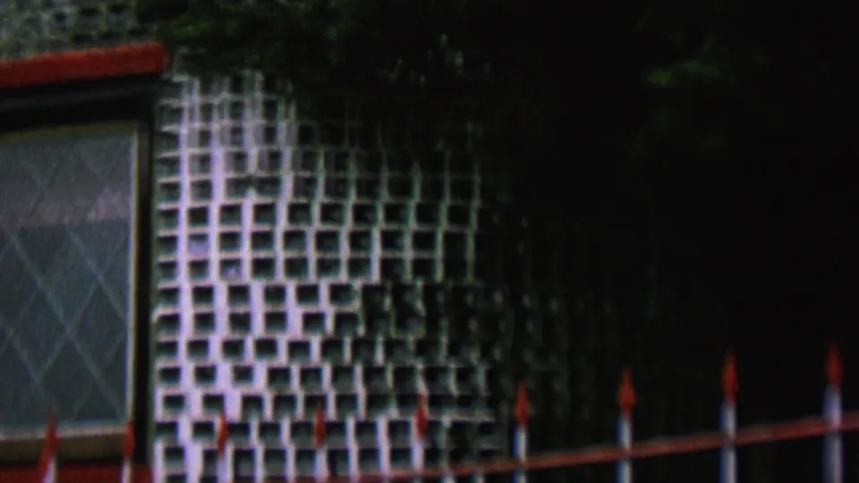 1962 St Paul frame showing the lower part of the tiled facade with a partial diamond-paned window and a fence with red-tipped posts in front.