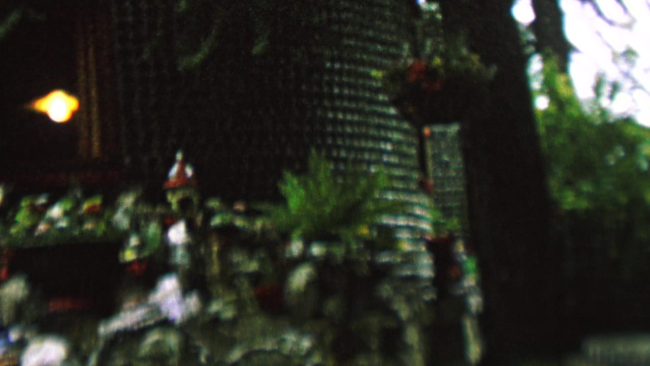 Close view of the decorative display with figurines, plants, bottle wall texture, and a glowing lamp.