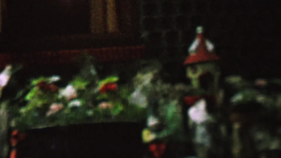 Dim 8mm frame of the St. Paul decorative display, with small garden structures, rocks, plants, and fantasy figurines under warm interior lighting.