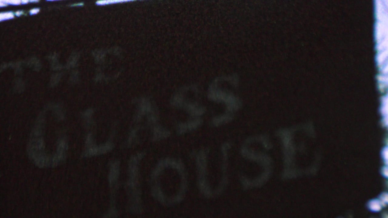 1962 St. Paul 8mm frame showing a dark, shadowed sign with faded white lettering that appears to read The Glass House.