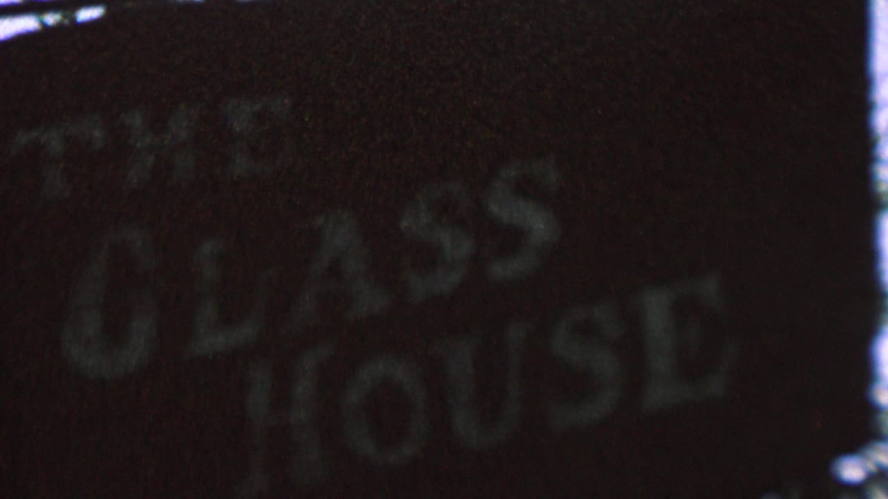 Closer view of the faded Glass House lettering on a dark sign.