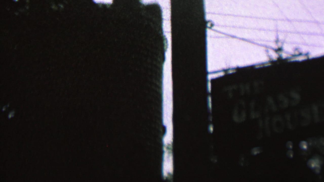 Dark vertical structure with a partially visible sign and overhead wires.