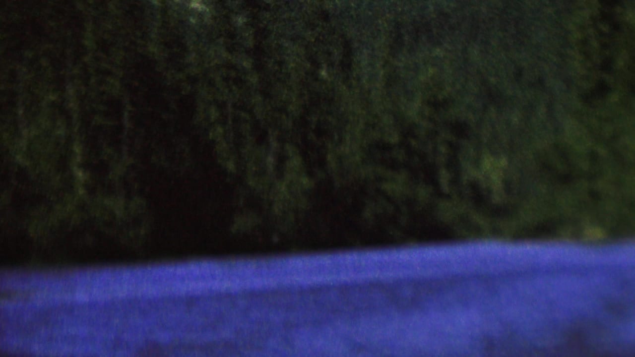 1962 8mm home-movie frame from the supplied St. Paul, Minnesota clip showing a dark tree-lined riverbank and blue-purple water under low light.