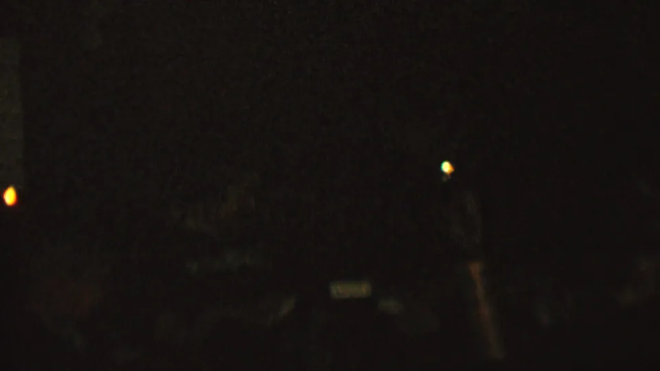 Very dark 1962 8mm home-movie frame from the supplied St. Paul, Minnesota metadata, showing scattered candlelike light points and barely visible interior shapes.
