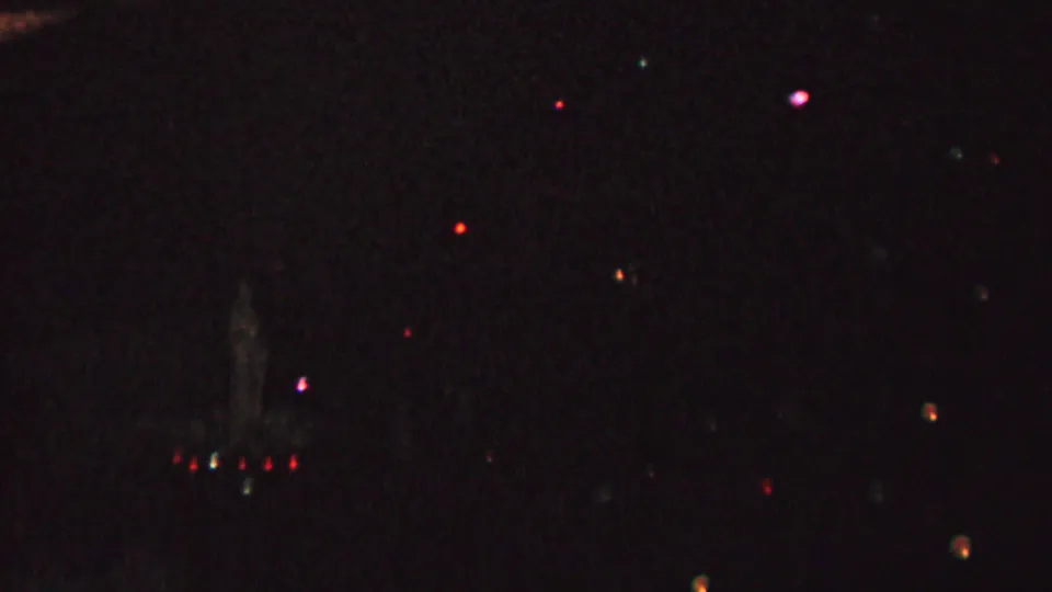 Metadata-supported 1962 St. Paul home-movie frame showing scattered city lights across a mostly black night scene with indistinct lower-edge forms.