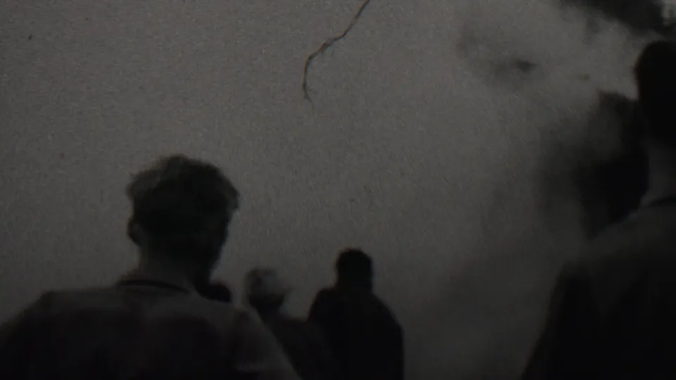A rear view of a man and nearby onlookers watching a dark smoke or fume cloud in archival 8mm footage associated with Trenton, New Jersey, 1937.