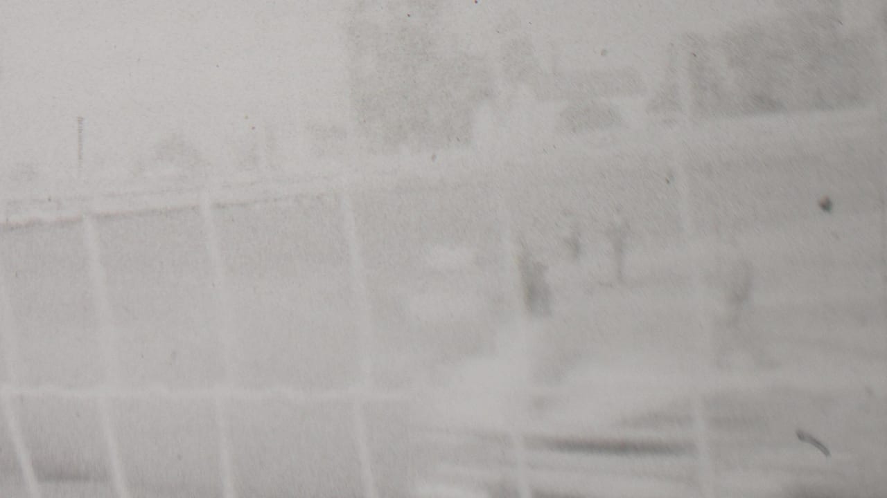 Overexposed frame from the 1937 Trenton home-movie racing footage, with faint fence geometry and indistinct trackside background visible through film haze.